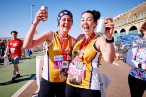 Two runners running for Grassroots Suicide Prevention celebrating completing the Brighton Half